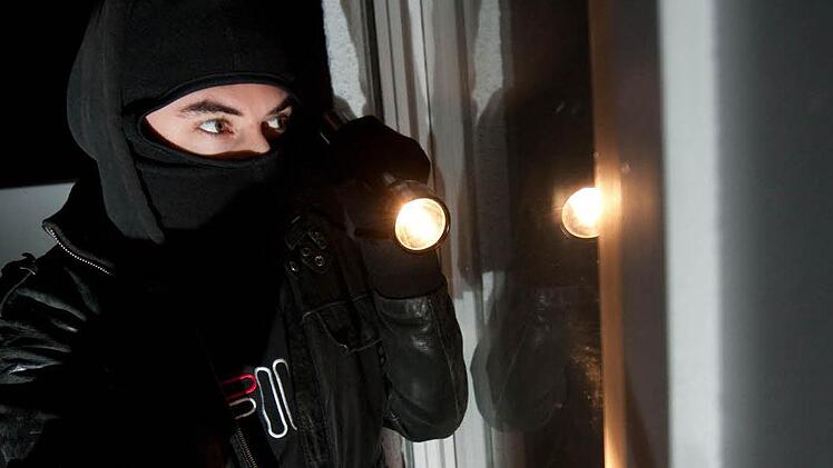 Auf diesem gestellten Bild versucht ein Einbrecher, durch ein Fenster in eine Wohnung einzudringen. Foto: Andreas Gebert, dpa