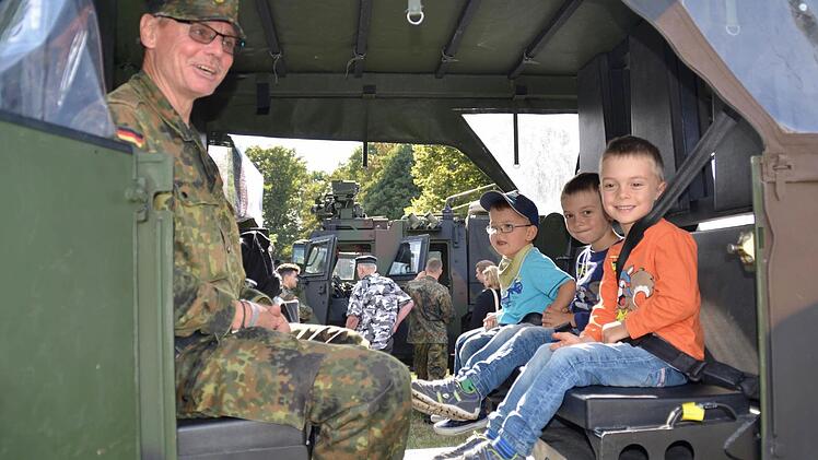 Die Kinder, wie hier Hannes (von rechts), Simon und Jonathan liebten es, in den Fahrzeugen Probe zu sitzen. Sie werden von Andreas Blesch beaufsichtigt, Zivilkraftfahrer am Bundeswehrstandort Hammelburg. Foto: Kathrin Kupka-Hahn