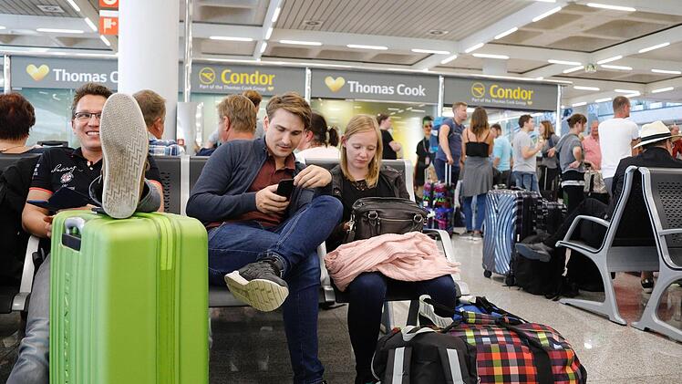 Geduldig warten diese Passagiere in der Nähe des Büros von Condor und Thomas Cook im Flughafen Palma de Mallorca auf Infos zu ihrem Rückflug.  Foto: Clara Margais/dpa