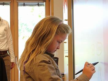Sabine kringelt am Whiteboard ihren Namen ein. Im Hintergrund ist ihre Lehrerin Beate Schneider zu sehen. Foto: Corinna Igler