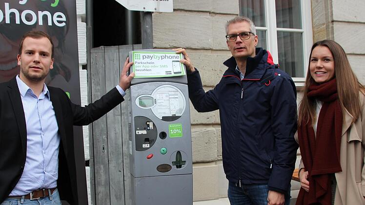 Firmenvertreter Fabian Grief (links), OB Uwe Kirschstein und Citymanagerin Elena Büttner bringen den letzten Informationsaufkleber für das Handy-Parken am Automaten an. Foto: Mirjam Stumpf