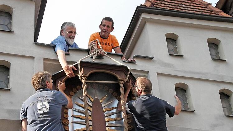 Ewald Baumeister und Bruno Eckert ziehen von oben, während Stefan Lochner und Norbert Düring das Kapellchen in die Verankerung heben.