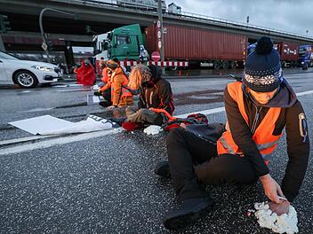 Einige Aktivisten kleben sich mit Sekundenkleber und Bauschaum an der Fahrbahn fest. Foto: Christian Charisius/dpa +++ dpa-Bildfunk +++