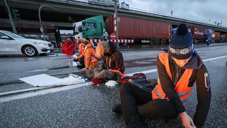 Einige Aktivisten kleben sich mit Sekundenkleber und Bauschaum an der Fahrbahn fest. Foto: Christian Charisius/dpa +++ dpa-Bildfunk +++