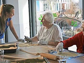 Gemeinsames Kochen mit der Ergotherapeutin fördert und erhält die geistigen Fähigkeiten, die Koordination und das manuelle Geschick der Patienten. Ergotherapeutin Linda Gagel in der Weihnachtsbäckerei mit Ingrid Leitner und Anny Greiner (von links).  Foto: Marco Heumann