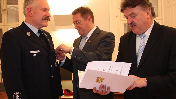 Seit 40 Jahren ist Manfred Täuber (links) aktiver Feuerwehrmann bei der Kulmbacher Wehr. Dafür ehrte ihn Oberbürgermeister Henry Schramm im Beisein von Landrat Klaus Peter Söllner (rechts) mit dem Staatlichen Ehrenkreuz in Gold.  Foto: Stephan Stöckel