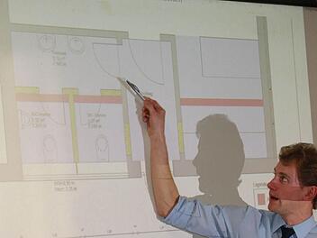 Der Vorsitzende des Feuerwehrvereins, Anton Gerstenkorn, stellte den Plan für die neue Raumsituation vor. Die rot markierten Wände werden entfernt, gelb markierte Wände werden neu errichtet. So soll der gesamte Toilettenbereich freundlicher und angenehmer gestaltet werden. Foto: Katharina Becht
