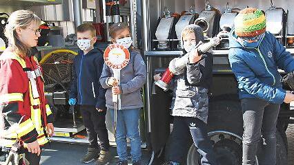 Lena Schwanert erkl&auml;rt den Kindern die Feuerwehrausr&uuml;stung. Dabei durften sie einmal selbst Hand anlegen.