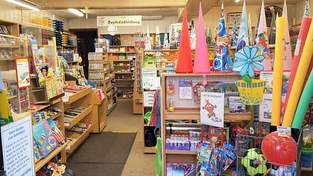 Ein Schreibwarengeschäft mit Regalen voller Schulmaterialien und Bastelbedarf. Bunte Schulutensilien und Schultüten prägen das Bild. Der Laden bereitet sich auf die Schließung vor.