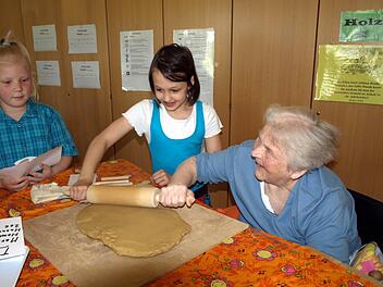 Gemeinsam geht es besser - Ottilie Schnappauf (rechts) rollt gemeinsam mit Maria den Tonteig aus während Zoe das Papiermuster der Ente begutachtet. Foto: Susanne Deuerling
