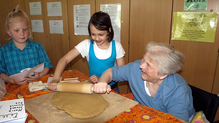 Gemeinsam geht es besser - Ottilie Schnappauf (rechts) rollt gemeinsam mit Maria den Tonteig aus während Zoe das Papiermuster der Ente begutachtet. Foto: Susanne Deuerling