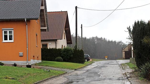 Diese Ortsstra&szlig;e soll im Rahmen der Dorferneuerung saniert werden. Im Hintergrund das Ortsschild in Richtung Horbach. Direkt an die vorhandene Ortsbebauung soll sich das neue Baugebiet Schleifweg&auml;cker anschlie&szlig;en.