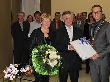 Bürgermeister Bezold (r.) ehrt seinen Vorgänger Gerhard Schmitt und beschenkt dessen Frau mit einem Blumenstrauß.  Foto: fra-press