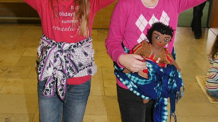 "Das ist ganz schön anstrengend, Wasser oder andere Sachen auf dem Kopf zu tragen", findet Patrizia Straßner (8, rechts). "Meistens werden die Babys allerdings auf dem Rücken getragen", zeigt Lisa Schmidt (8, links).