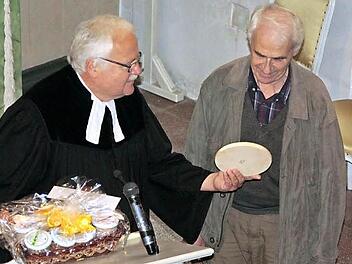 Pfarrer Albrecht Bischoff übergibt ein Geschenk als Dankeschön an den seit 55 Jahren im Ehrenamt wirkendenen Tippach-Hüttenwart Heinrich Zschach.  Foto: Simone Büttner