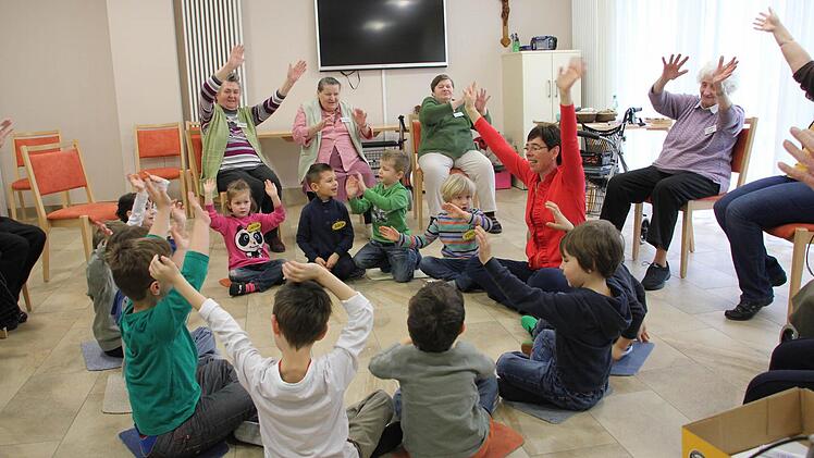 Bewegung und Singen: Die Buben und Mädchen und die Senioren wirken mit beim Musikprojekt "Unter sieben - über 70". Die Singschullehrerin Monika Schraut (rechts im Kreis der Kinder) leitet Jung und Alt an.