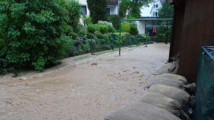 Drei, vier Meter breit wälzt sich die  reißende Flut am Wohnhaus der Familie Schrenker in Petzmannsberg vorbei. Die Sandsäcke verhindern, dass die braune Brühe über die Mauer läuft. Foto: privat