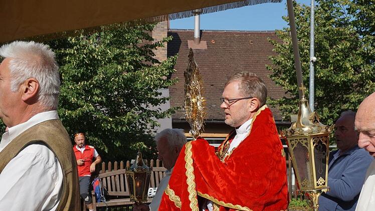 Domkapitular Jürgen Vorndran kam die Ehre zuteil, das Allerheiligste  bei der Prozession zur Kreuzerhöhung um die Klosterkirche am Kreuzberg  zu tragen. Foto: Marion Eckert