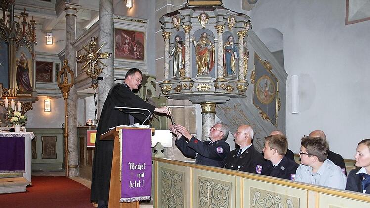 Pfarrer Wolfgang Oertel überreichte den Mitgliedern der Feuerwehr die Attribute, die einst auf dem Untersteinacher Kirchturm waren: ein Hahn und eine Sonne. Foto: Sonny Adam