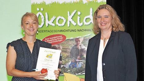 Staatsministerin Kerstin Schreyer (rechts) &uuml;berreicht Kindergartenleiterin Karin Vonbrunn die Urkunde. Foto: pr