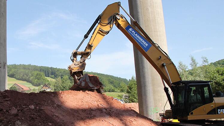 Bagger schütten Erdwälle auf, die als Fallbetten die Brücke auffangen sollen.