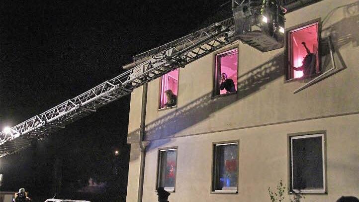 Mit einer Drehleiter werden Menschen aus dem ersten Stock gerettet.