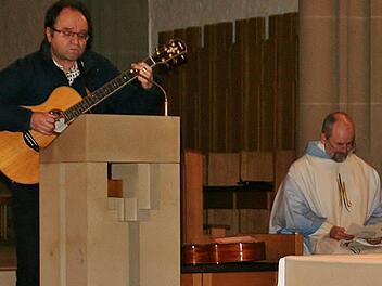 Liedermacher Franz-Josef Tremer singt in der Bad Kissinger Stadtpfarrkirche: "Franz Reinisch, du verehrter, du bist ganz Mensch und Christ", rechts Pfarrer Armin Haas. Foto: Werner Vogel