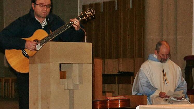 Liedermacher Franz-Josef Tremer singt in der Bad Kissinger Stadtpfarrkirche: "Franz Reinisch, du verehrter, du bist ganz Mensch und Christ", rechts Pfarrer Armin Haas. Foto: Werner Vogel