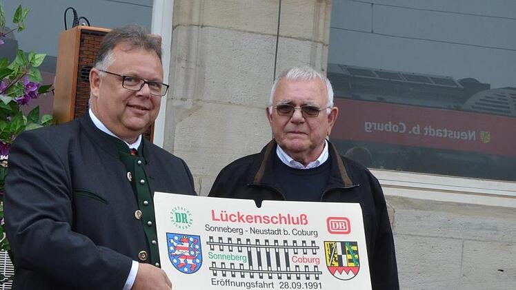 Ernst Fleischmann (rechts) überreicht ein historisches Schild an Martin Stingl. Es erinnert an die Fahrt zum Lückenschluss 1991.