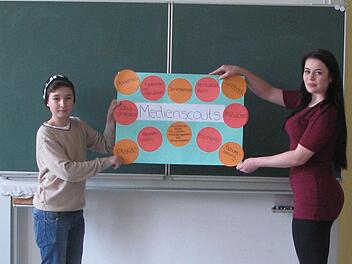 Florian Wolf und Sina Heller, die zum Medienscout ausgebildet worden sind, hängen ein Plakat im Klassenzimmer auf. Foto: Daniela Pondelicek