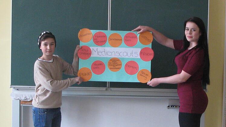 Florian Wolf und Sina Heller, die zum Medienscout ausgebildet worden sind, hängen ein Plakat im Klassenzimmer auf. Foto: Daniela Pondelicek