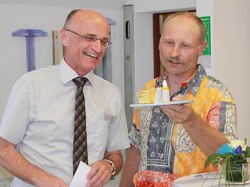 Landrat Wilhelm Schneider freut sich sichtlich über den golden glänzenden Stein aus Maroldsweisach, den ihm Obermeister Michael Ott überreicht.  Foto: Katharina Becht