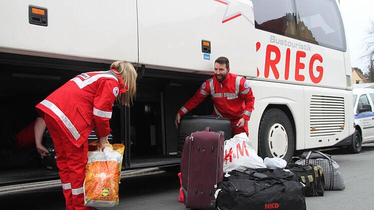BRK-Helfer luden die Koffer der Flüchtlinge aus dem Bus.