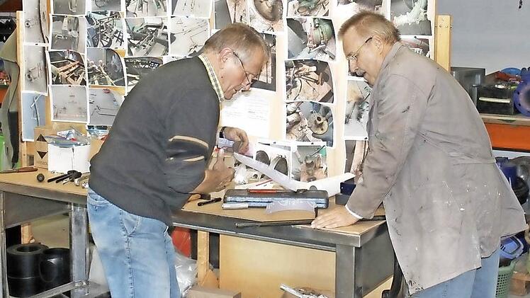 Harry Dees und Lothar Hoffmann bereiten ein Teil für den Wiedereinbau vor. Im Hintergrund eine Fotodokumentation. Foto: Mäuser