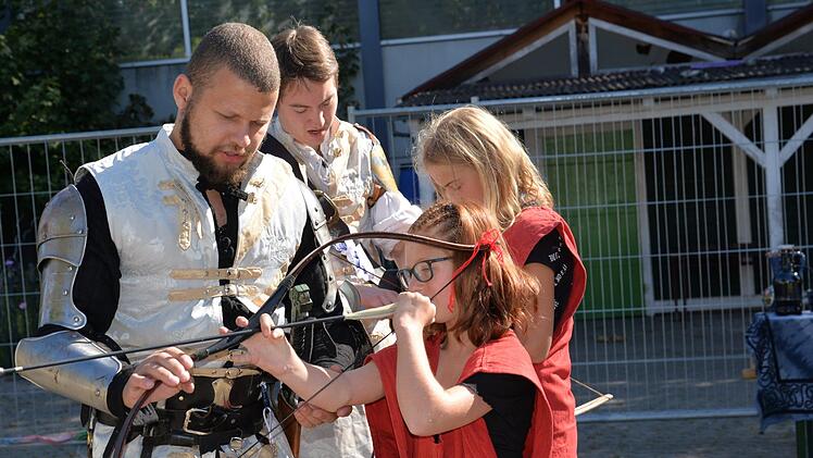 Edwin und Dorian zeigen den beiden Mädchen, wie man den Pfeil richtig in den Bogen spannt.  Foto: Franka Struve