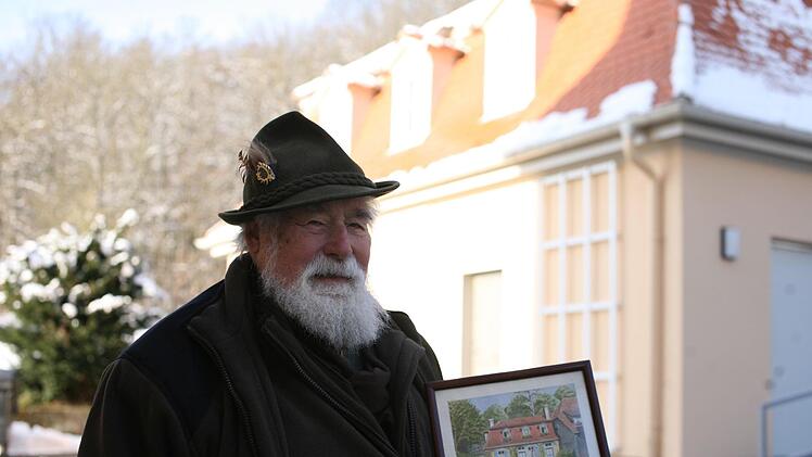Siegfried Ritter mit einem gemalten Bild, das einen Teil seines Elternhauses im Jahr 1941 zeigt. Der Geb&auml;udekomplex ist verschwunden, wurde nur teilweise wieder aufgebaut. Der 83-J&auml;hrige hingegen hat ihn &uuml;berdauert, verbrachte fast sein ganzes Leben im Staatsbad. Foto: Steffen Standke