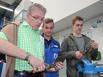 Bleche schneiden ist gar nicht so einfach. Diese Erfahrung machen beim Aktionstrag Vater Thomas Wulf (links) und sein Sohn Alexander (rechts). Lehrling Waldemar Geffel von der Maschinenfabrik Fischer schaut ihnen bei der Arbeit über die Schulter.  Foto: Stephan Stöckel