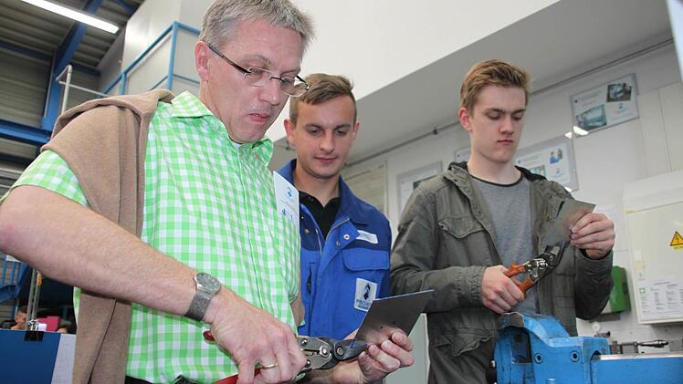 Bleche schneiden ist gar nicht so einfach. Diese Erfahrung machen beim Aktionstrag Vater Thomas Wulf (links) und sein Sohn Alexander (rechts). Lehrling Waldemar Geffel von der Maschinenfabrik Fischer schaut ihnen bei der Arbeit über die Schulter.  Foto: Stephan Stöckel