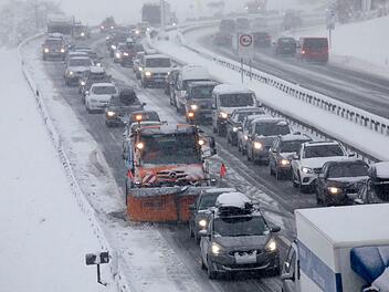 Siegsdorf: Ein Fahrzeug vom Winterdienst steht im Stau auf der verschneiten Autobahn A8 bei Siegsdorf, wo Bäume am Straßenrand umgefallen sind. Foto: Bernd März/dpa