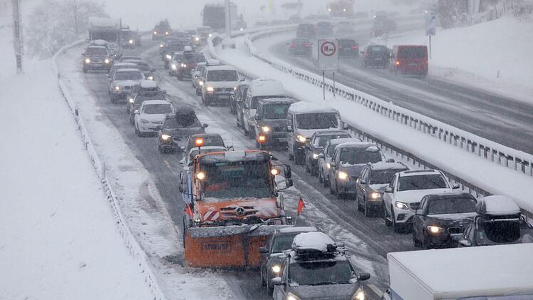 Siegsdorf: Ein Fahrzeug vom Winterdienst steht im Stau auf der verschneiten Autobahn A8 bei Siegsdorf, wo Bäume am Straßenrand umgefallen sind. Foto: Bernd März/dpa