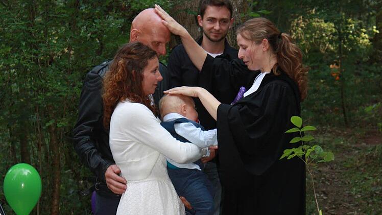 Vikarin Johanna Thein segnet Mama Simone, Patenonkel Andy, den kleinen Elljot und Papa Frank bei der Taufe im Wald. Foto: Henning Schuster