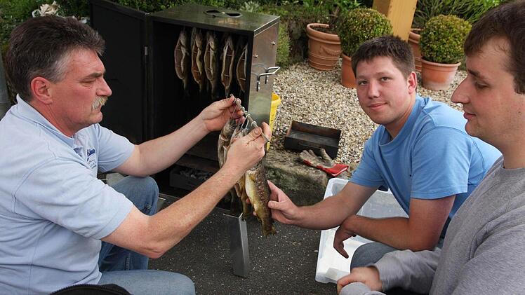 Markus Hofmann, Jürgen Putz und Daniel Stein (v.l.) grillen Forellen.