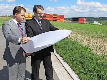 Auf diesem Gelände in Schlüsselfeld wollen David Veit Krafft (links) und Matthias Gebhardt aus der Geschäftsleitung der Dennert Poraver GmbH ihre Pläne realisieren und ein drittes Werk für Blähglas-Granulat bauen. Im Hintergrund das Areal der Firma Pröls und der ADAC. Foto: Andreas Dorsch