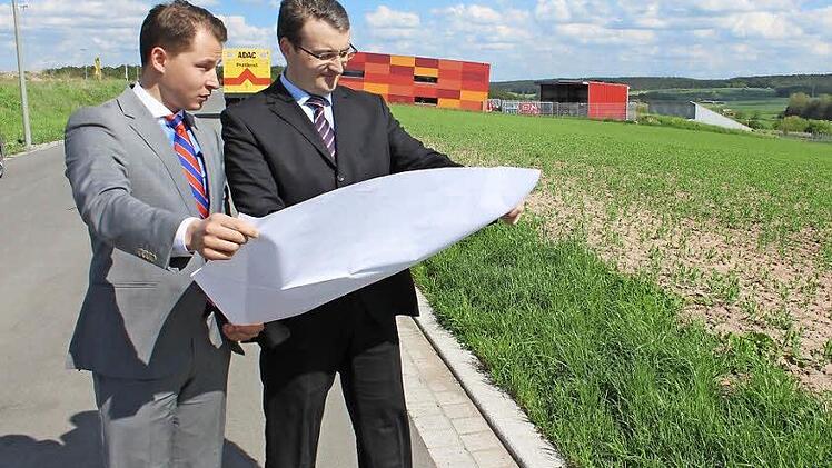 Auf diesem Gelände in Schlüsselfeld wollen David Veit Krafft (links) und Matthias Gebhardt aus der Geschäftsleitung der Dennert Poraver GmbH ihre Pläne realisieren und ein drittes Werk für Blähglas-Granulat bauen. Im Hintergrund das Areal der Firma Pröls und der ADAC. Foto: Andreas Dorsch