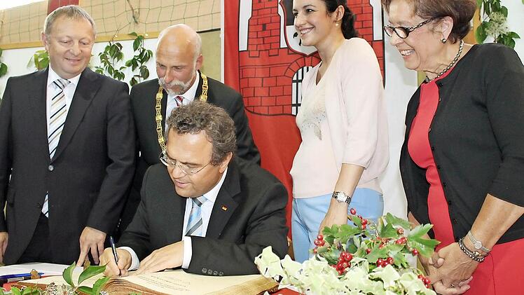 Bundesinnenminister Hans-Peter Friedrich (vorne) beim Eintrag ins goldene Buch der Stadt. (Hinten von links) Thomas Bold, Kay Blankenburg, Dorothee Bär und Karin Renner schauen ihm über die Schulter.