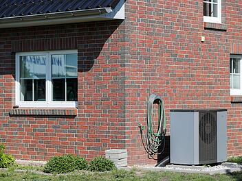 Eine Luft-Wasser-W&auml;rmepumpe steht vor einem Haus