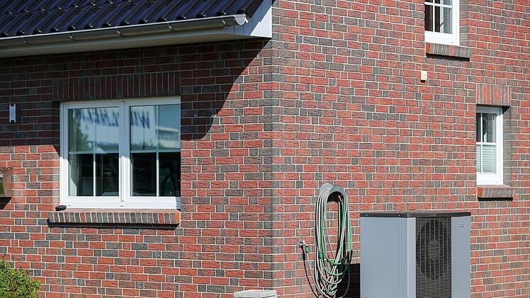 Eine Luft-Wasser-W&auml;rmepumpe steht vor einem Haus