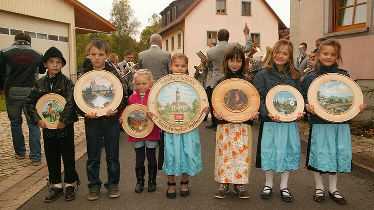 Die Buben und Mädchen zeigen die Schützenscheiben beim Kirchweihumzug.  Fotos: amo