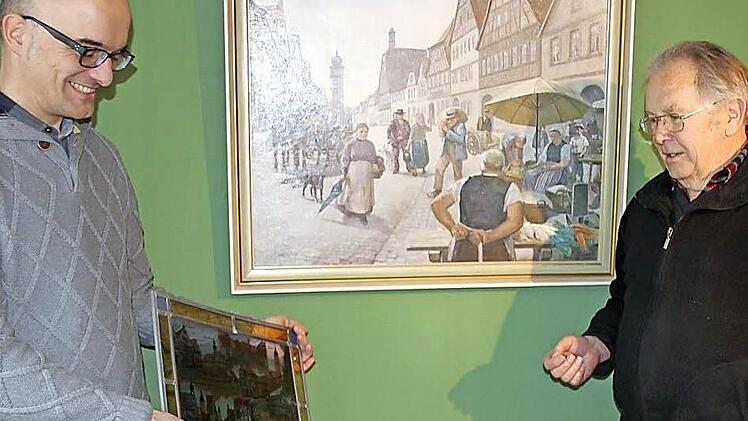 Das Leben in der Stadt zeigt das Gemälde im Hintergrund, das Stefan Andritschke (links) und Ingo Hafenecker ebenso beeindruckt wie die Glasmalerei, die der Ausstellungsleiter in Händen hält. Foto: Ralf Kestel