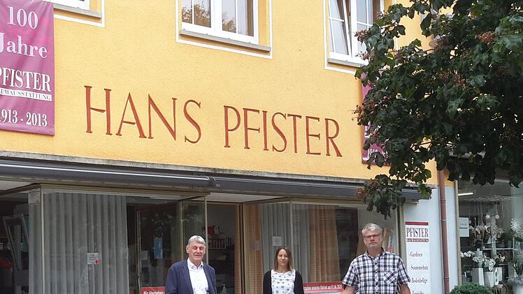 Nicht mit dem symbolischen Schlüssel, sondern zur Branche passend mit einer Stoffrolle übergab Jürgen Pfister (links) seinen Bad Brückenauer Geschäftsbetrieb an Jürgen Bergander (rechts). Ansprechpartnerin vor Ort in der Ludwigstrasse ist für die Kunden weiterhin die Raumausstatterin Martina Arnold (Bildmitte).Foto: Rolf Pralle